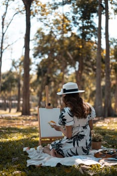 Calm young woman in casual clothes painting picture in autumn park. Mindfulness, art therapy and creative hobbies concept.