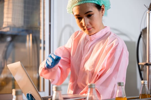 Quality manager a woman meticulously inspects beverage bottles on a factory conveyor belt. Using a laptop she ensures stringent liquid quality control.