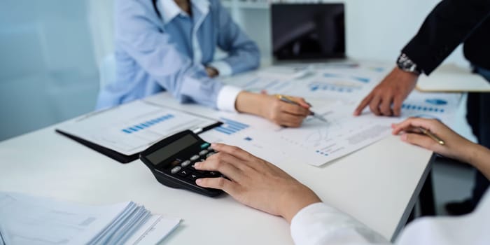 Businesswoman using a calculator to calculate numbers on a company's financial documents, she is analyzing historical financial data to plan how to grow the company. Financial concept.