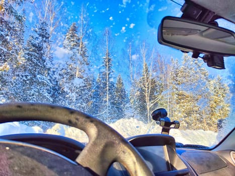 Snow on the windshield and Snowy Road View From Inside a Car During Winter Day. Snowfall on the road in nature forest. Car interior in winter travel