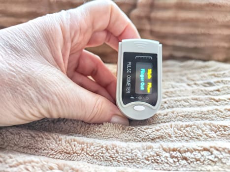 Close up of hand with a pulse oximeter on the finger.