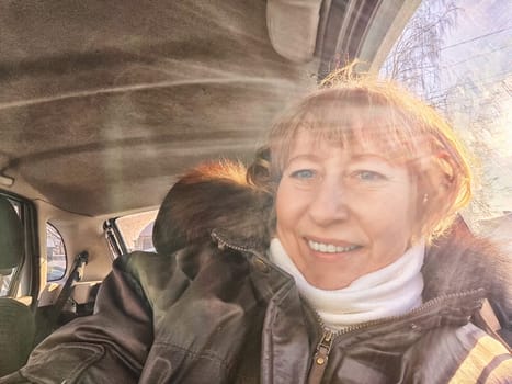A woman in a car taking a selfie while enjoying a drive. Female driver posing inside car and the rays of the sun in the background