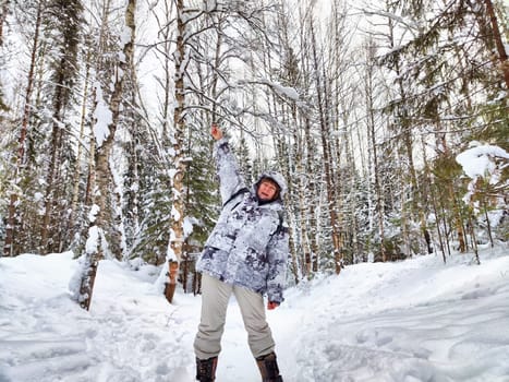 Cheerful middle aged woman in a winter warm sports jacket taking selfie on cold snow forest in nature outdoors