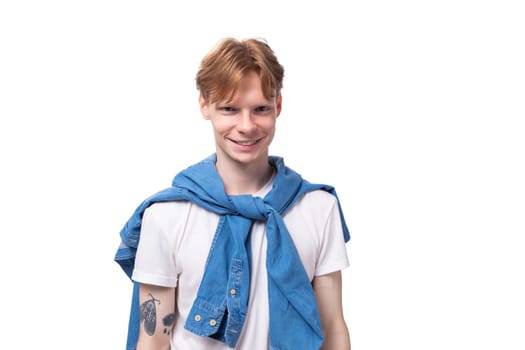 young positive red-haired man with a short haircut with a tattoo on his arms wearing a white t-shirt.