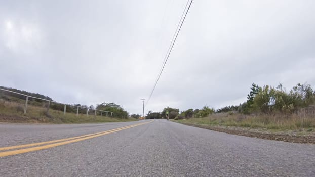 Vehicle navigates the streets of Morro Bay, California, during a cloudy winter day. The atmosphere is moody and serene as the overcast sky casts a soft light on the charming buildings and quiet streets of this coastal town.