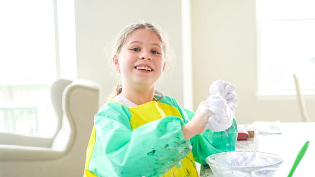 In a modern kitchen, a homeschooled girl is engrossed in creating homemade slime, a fun and educational hands-on project that enhances her creativity and problem-solving skills.