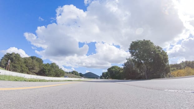 On a clear winter day, a car smoothly travels along Highway 101 near Santa Maria, California, under a brilliant blue sky, surrounded by a blend of greenery and golden hues.