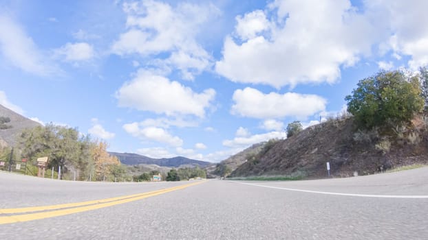 Vehicle is cruising along the Cuyama Highway under the bright sun. The surrounding landscape is illuminated by the radiant sunshine, creating a picturesque and inviting scene as the car travels through this captivating area.