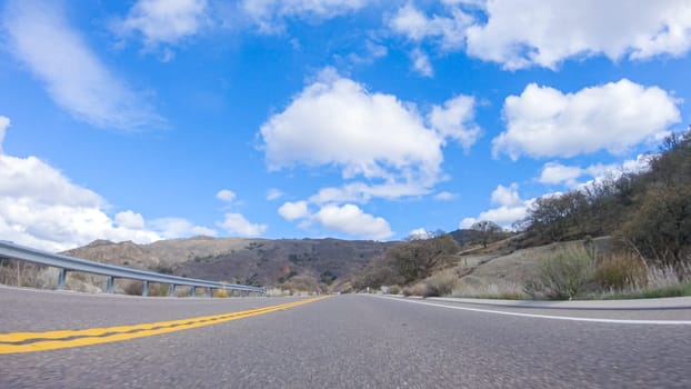 Vehicle is cruising along the Cuyama Highway under the bright sun. The surrounding landscape is illuminated by the radiant sunshine, creating a picturesque and inviting scene as the car travels through this captivating area.