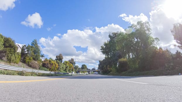 On a clear winter day, a car smoothly travels along Highway 101 near Santa Maria, California, under a brilliant blue sky, surrounded by a blend of greenery and golden hues.