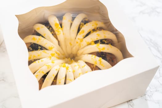 The freshly baked bundt cakes are carefully nestled into white paper boxes, preparing them for secure transportation while maintaining their delectable appearance.