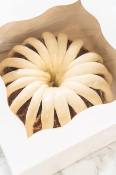 The freshly baked bundt cakes are carefully nestled into white paper boxes, preparing them for secure transportation while maintaining their delectable appearance.