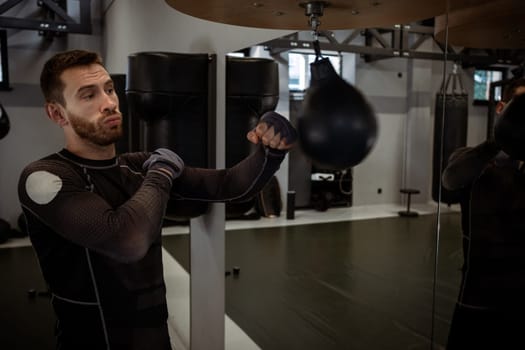 Young adult boxer focused on strengthening arm muscles, improving punch accuracy and timing with speed bag in modern boxing gym