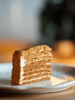 Slice of layered honey cake selective focus. Perfect piece of layered honey cake in restaurant bokeh background. Traditional Russian layer cake Medovik made with honey