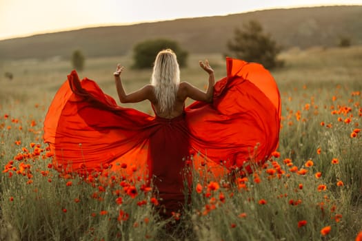 Woman poppy field red dress sunset. Happy woman in a long red dress in a beautiful large poppy field. Blond stands with her back posing on a large field of red poppies.