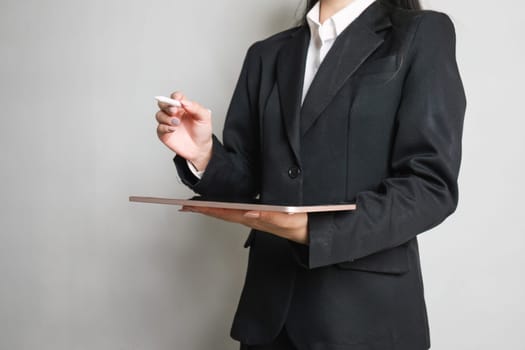 Close up smart Asian businesswoman holding her tablet and pointing tablet is pen up on empty space.