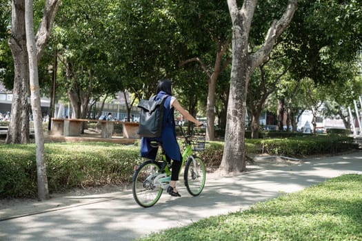 Asian businesswoman rides a bicycle to work in the office to reduce air pollution and protect the environment..