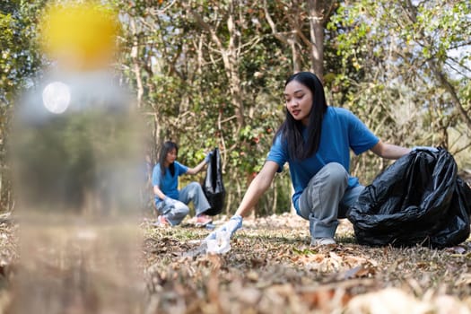 A group of Asian volunteers collects trash in plastic bags and cleaning areas in the forest to preserve the natural ecosystem..