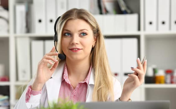 A beautiful feminine blonde doctor talking to patient over wireless headset advises a medical problem the formation of remote education internship callcenter specialist