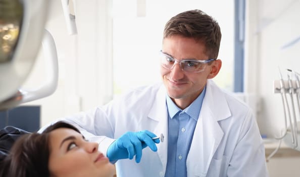 A woman at the reception of a male dentist examining teeth and oral cavity