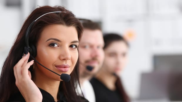 Three call centre service operators at work. Portrait of smiling pretty brunette woman at workplace employment effective mediation negotiation participation solve problem real time aid job concept