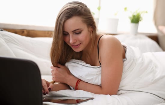 young blond beautiful woman work winh tablet stay in bed early morning