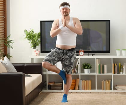 A young man practicing yoga and Pilates at home dreams of an excellent figure being restored after an intense load for the body to lose weight.