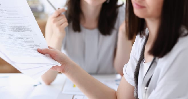 Group of people deliberate on problem with clipboard pad closeup. White collar check money papers stock exchange market earnings list partnership agreement discussion concept