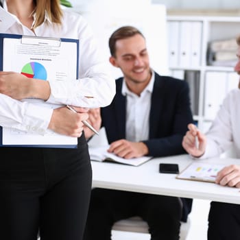 Female arms hold silver pen and pad with financial statistics at workplace closeup. White collar check money papers school or college homework exercise internal revenue Service inspector concept