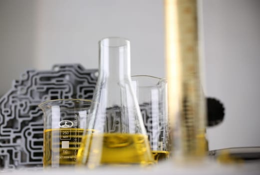 Test tube chemistry flask against background of hydroblock acp with yellow liquid purified oil from recycling and lubricating materials sale closeup