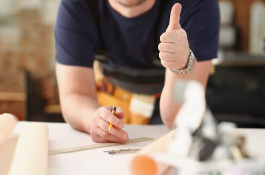 Smiling worker in yellow helmet show confirm sign with thumb up at arm portrait. Manual job DIY inspiration joinery startup idea fix shop hard hat industrial education profession career concept