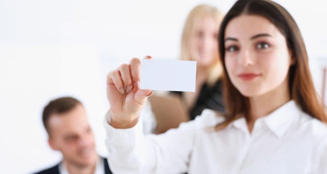 Female hand in suit give blank calling card to visitor closeup. White collar partners company name exchange executive or ceo introducing at conference product consultant sale clerk concept