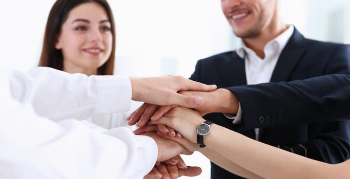 Group of people in suits crossed hands in pile for win closeup. White collar leadership high five cooperation initiative achievement corporate life style friendship deal heap stack concept