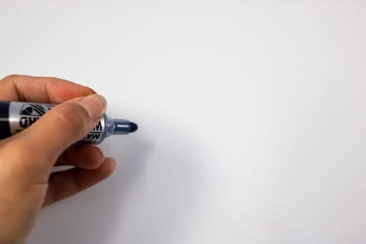 Hand with marker on whiteboard background close up