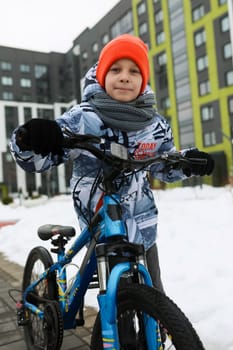 European child riding a bicycle in the yard in winter.