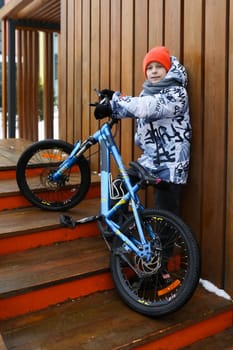 A boy in winter clothes rides a bicycle during the holidays.