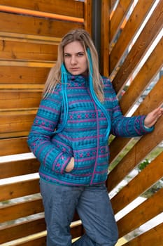 A cute woman with a blue colored strand in her hair is dressed in a blue jacket walking around the city.