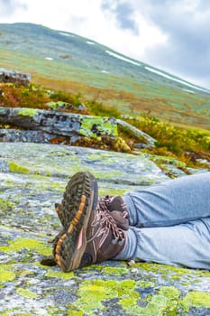 Hiking boots and womens legs on rock mountains in Rondane National Park Ringbu Innlandet Norway in Scandinavia.