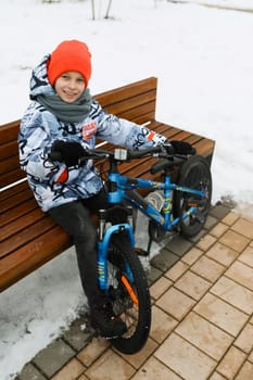 European child riding a bicycle in the yard in winter.