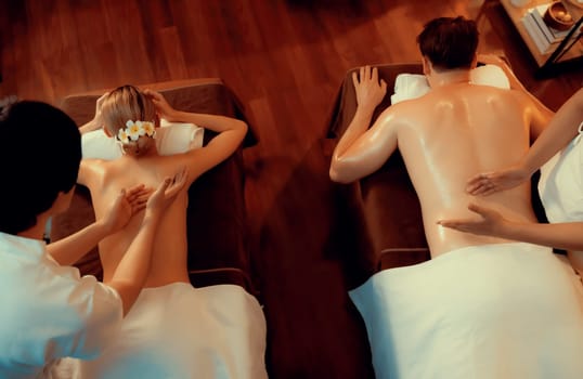 Top view couple customer enjoying relaxing anti-stress spa massage and pampering with beauty skin recreation leisure in warm candle lighting ambient salon spa at luxury resort or hotel. Quiescent