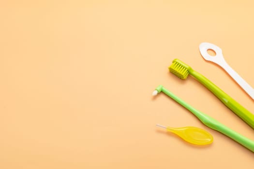 Design Individual Dental Oral Hygiene Set Kit. Dentistry White Tongue Scraper, Toothbrush, Interdental Toothbrush For Cleaning Between Teeth On Peach Yellow Background. Copy Space Horizontal Plane