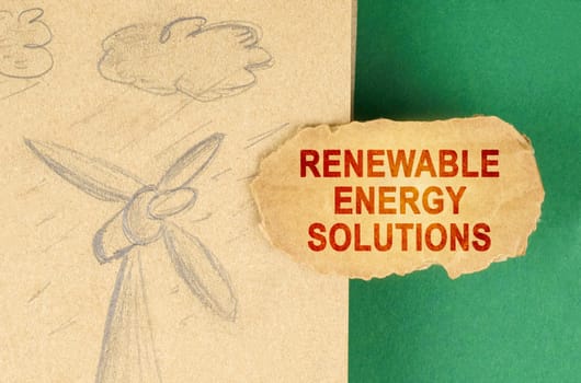 Alternative energy concept. On a green surface there is a drawing with a wind generator and a cardboard with the inscription - renewable energy solutions