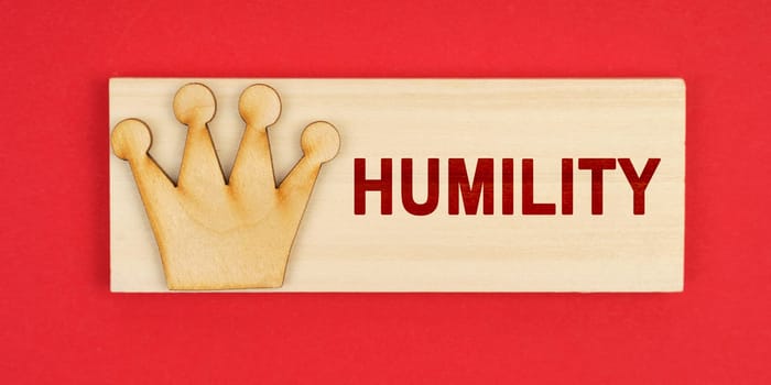 Leader concept. On a red surface there is a wooden block with the inscription - Humility