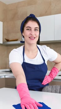 Professional cleaners in blue uniform washing floor and wiping dust from the furniture in the living room of the apartment. Cleaning service concept