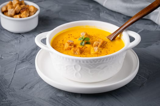 Pumpkin soup with croutons on grey background.