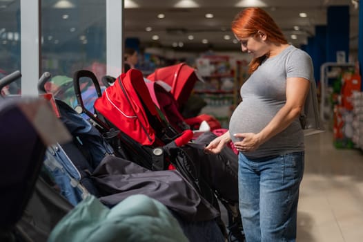 Red-haired pregnant woman chooses a stroller in a children's store