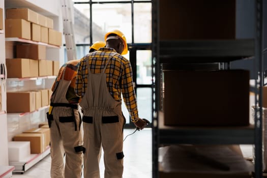 Retail storehouse employees scanning cardboard box, checking product in stock. African american distribution department workers managing logistics and doing goods inventory in stockroom