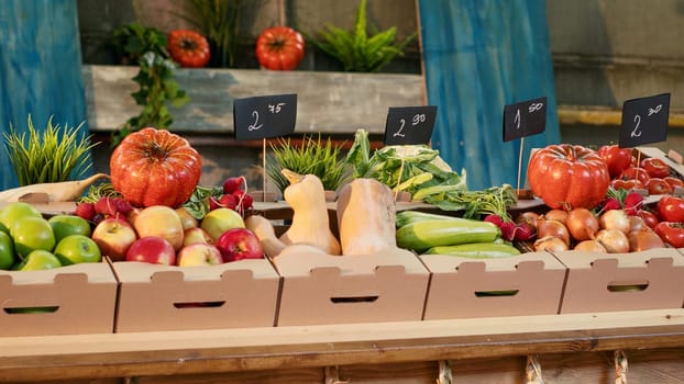 Boxes filled with organic fruits and vegetables placed on stand, fresh natural farming produce at outdoors food fair. Empty local farmers market counter with raw colorful healthy products.