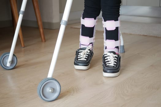 child with walking frame and knee orthosis outdoor .