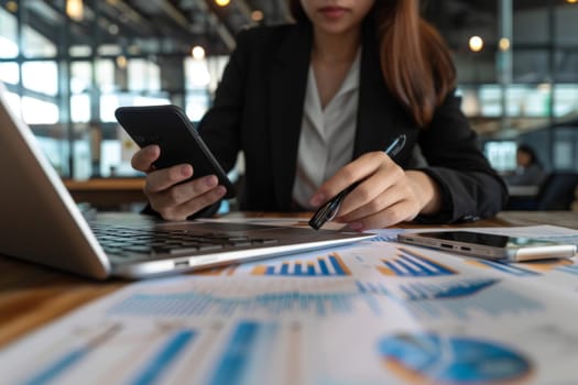 Close up of Businesswoman using smartphone while working on laptop.